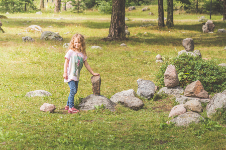 little girl in the Park climbed on the stonesの写真素材