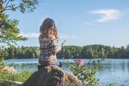 girl, a child on the lake in the woods eating fried bread in the campaignの写真素材