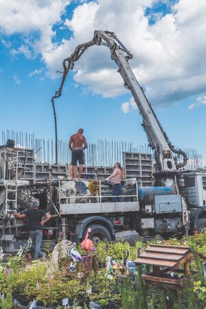 Russia, Leningrad oblast, the city of Nikolskoye, 08 Aug 2018 -construction, cement pouring with machine into the frame of the house, worker, manのeditorial素材