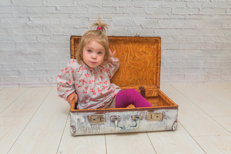 girl, child with suitcase on white brick wall backgroundの写真素材