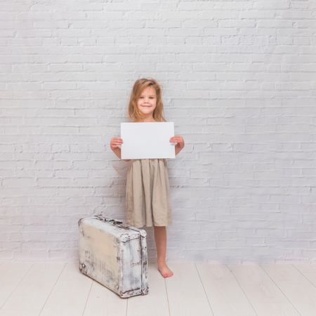 Copy Space girl, child with suitcase on white brick wall backgroundの写真素材
