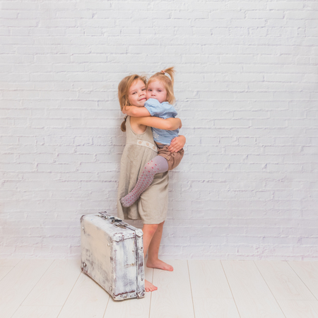 girl, child with suitcase on white brick wall backgroundの写真素材