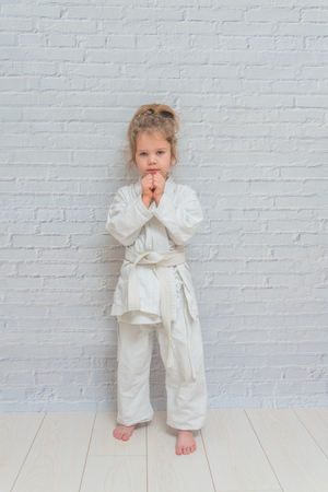 the girl, a child in a kimono on karate training works out blows and greetingの写真素材