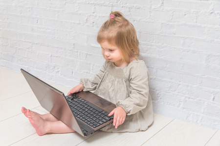 girl, child businesswoman working at a laptop, against a white brick wallの写真素材