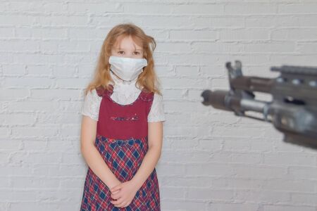 the girl with a gun and a mask on her face during the epidemicの写真素材
