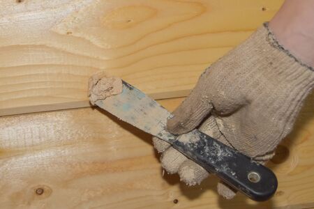 the worker puts putty on a hole in a wooden wallの写真素材
