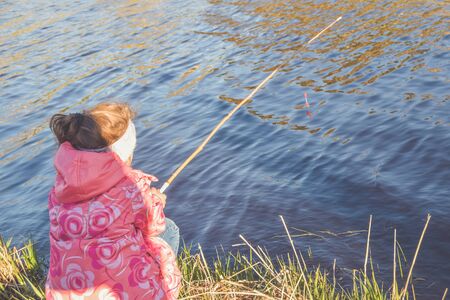 the child girl standing on the Bank fishingの写真素材