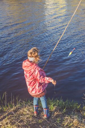 the child girl standing on the Bank fishingの写真素材
