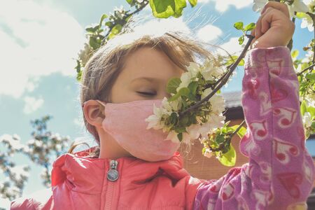 the child in mask sniffs flowers Allergy virus outsideの写真素材