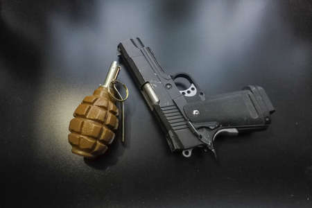 the black background a pistol and a hand grenade