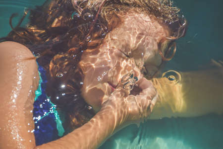 a girl child is splashing in the pool on the street