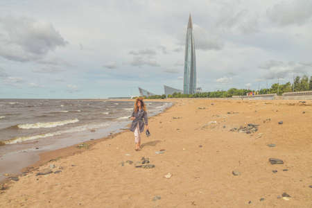 the girl with a in her hands on the embankment looks into the seaの写真素材