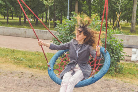 a girl swings on a swing in the park on a sunny dayの写真素材