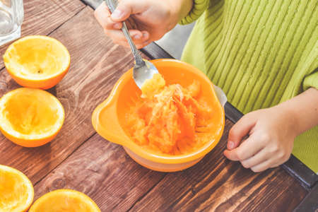 a girl child makes freshly squeezed orange juice on a manual juicerの写真素材
