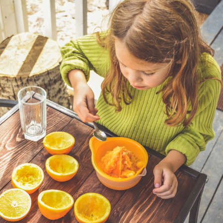 a girl child makes freshly squeezed orange juice on a manual juicerの写真素材