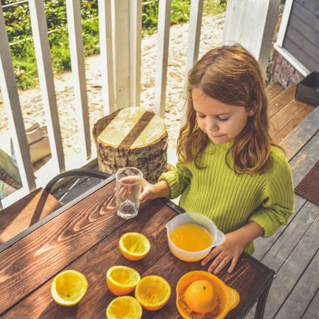 a girl child makes freshly squeezed orange juice on a manual juicerの写真素材