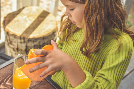 a girl child makes freshly squeezed orange juice on a manual juicerの写真素材