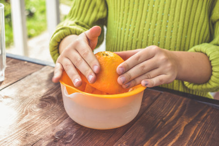 a girl child makes freshly squeezed orange juice on a manual juicer
