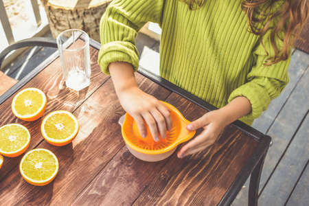 a girl child makes freshly squeezed orange juice on a manual juicerの写真素材
