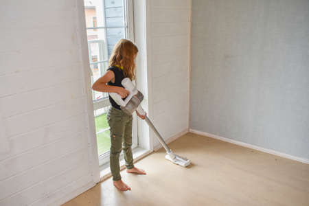 the child girl does vacuuming in the house photo without processingの写真素材