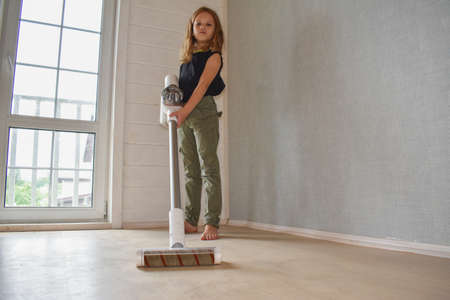 the child girl does vacuuming in the house photo without processingの写真素材