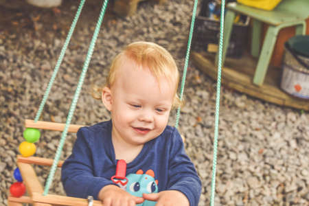 a happy baby boy on a swing outsideの写真素材
