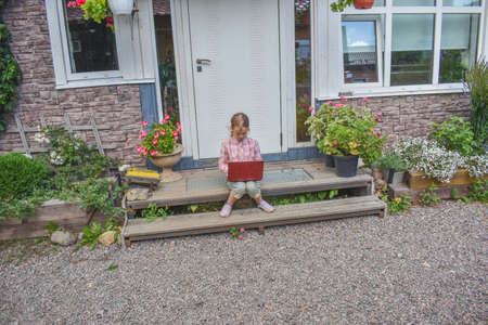 a girl child with a djembe drum outdoor on the porch of the house photo without processingの写真素材