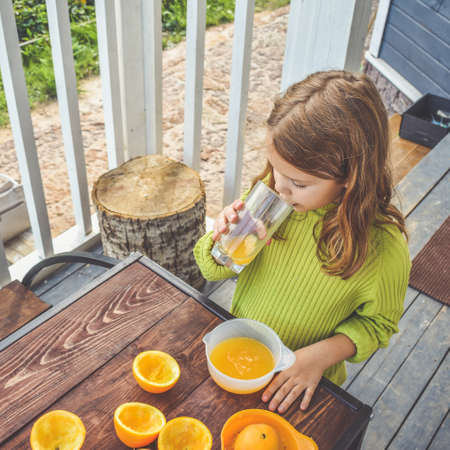 a girl child makes freshly squeezed orange juice on a manual juicerの写真素材