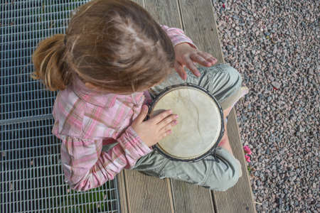 a girl child with a laptop is sitting on the porch of the house during a lesson on a remote photo without a filterの写真素材