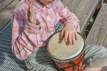 a girl child with a laptop is sitting on the porch of the house during a lesson on a remote photo without a filterの写真素材