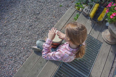 a girl child with a laptop is sitting on the porch of the house during a lesson on a remote photo without a filterの写真素材