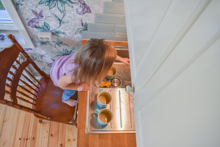 a child washes mugs in the sink photo without a filterの写真素材