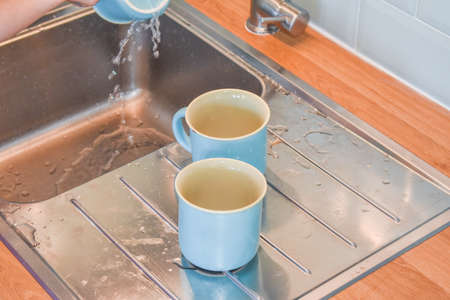 a child washes mugs in the sink photo without a filterの写真素材