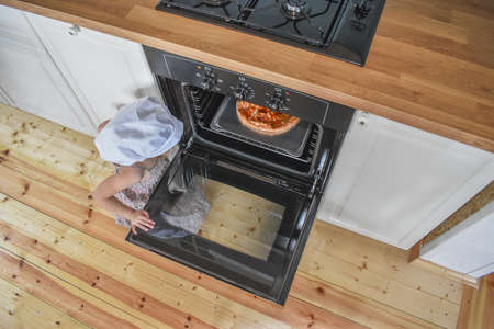 girl looking at pizza in the oven background.の写真素材