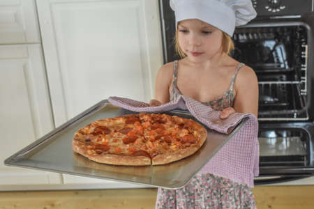 girl child cooks pizza in the oven photo without filterの写真素材