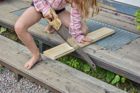 a child girl has damaged a bicycle wheel and is making repairs photo without processingの写真素材