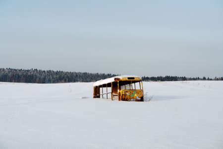 Frame of old bus in field in winter