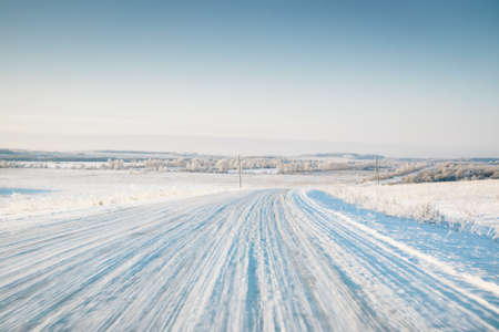 Empty winter road covered with snow on field in motionの写真素材