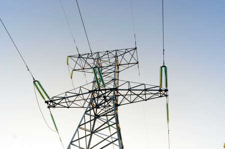 The tip end anchor metal supports of overhead power lines costs with wires and bundles of strands of high-voltage insulators against the clear blue sky.の写真素材