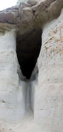 A cave in a clay gorge with overhanging rocks and darkness far away in Yakutia.の写真素材