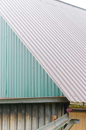Water from rain flows over the edge of the roof of a village house in the gutter and flows on. Collection of drinking water of the Northern peoples of Yakutia.の写真素材