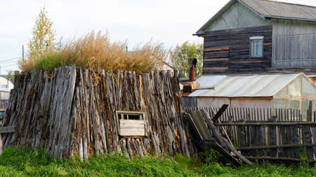 The room for cattle khoton, made of cow dung and wood, overgrown with grass stands on a plot with a house and a greenhouse in the North of Yakutia.の写真素材