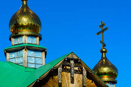 Yakut patterns under the roof of the Orthodox Church with Golden domes and crosses made of wood against the blue sky.の写真素材
