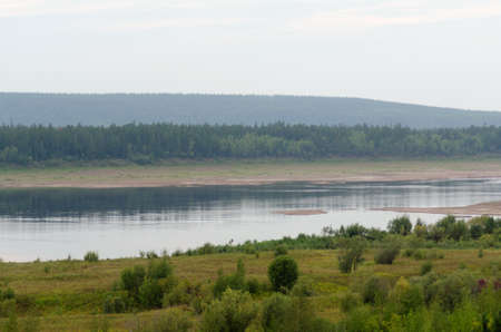 Wild Northern Yakut river Vilyui in Russia, flows through the tundra with overgrown banks on the background of spruce forests of the taiga summer day.の写真素材