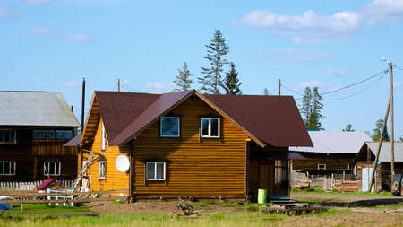 A new private cottage of yellow logs, among the old village houses, is being completed in the summer in Yakutia in the village of Suntar.の写真素材