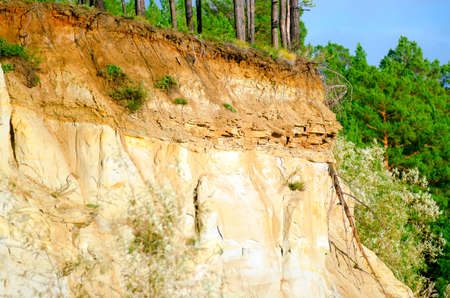 Layers of earth on a clay cliff under a spruce forest with layers of stones in the Northern taiga of Yakutia.の写真素材