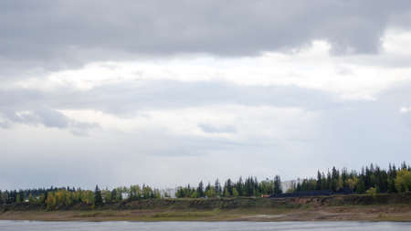 The Viluy river flows past the shore with the village of North ulus Suntar on the shore with storage in petrol tanks at the gas station and piles of coal fuel.の写真素材