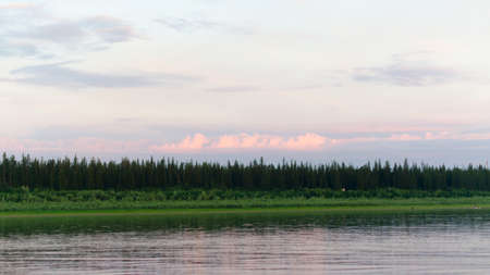 The shore of the wild Northern river Viluy at the beginning of the spruce taiga and silhouettes of people and boats.の写真素材