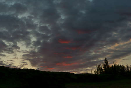 Ublic from catching the sunset on the clouds in the sky the hill with a small round sign to the forest.の写真素材