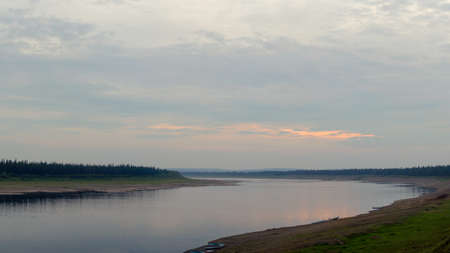 Boats and boats occasionally stand on the banks of the Northern river Viluy in the wild taiga of Yakutia in the evening.の写真素材